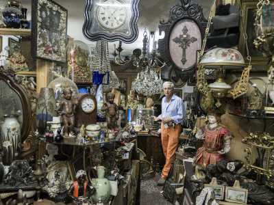 Seguiamo l�antiquario lungo un corridoio strettissimo che conduce al retro bottega. Da una parte e dall�altra non possiamo fare a meno di notare antichi specchi, piccolissimi giocattoli degli anni 40, lampade ad olio...